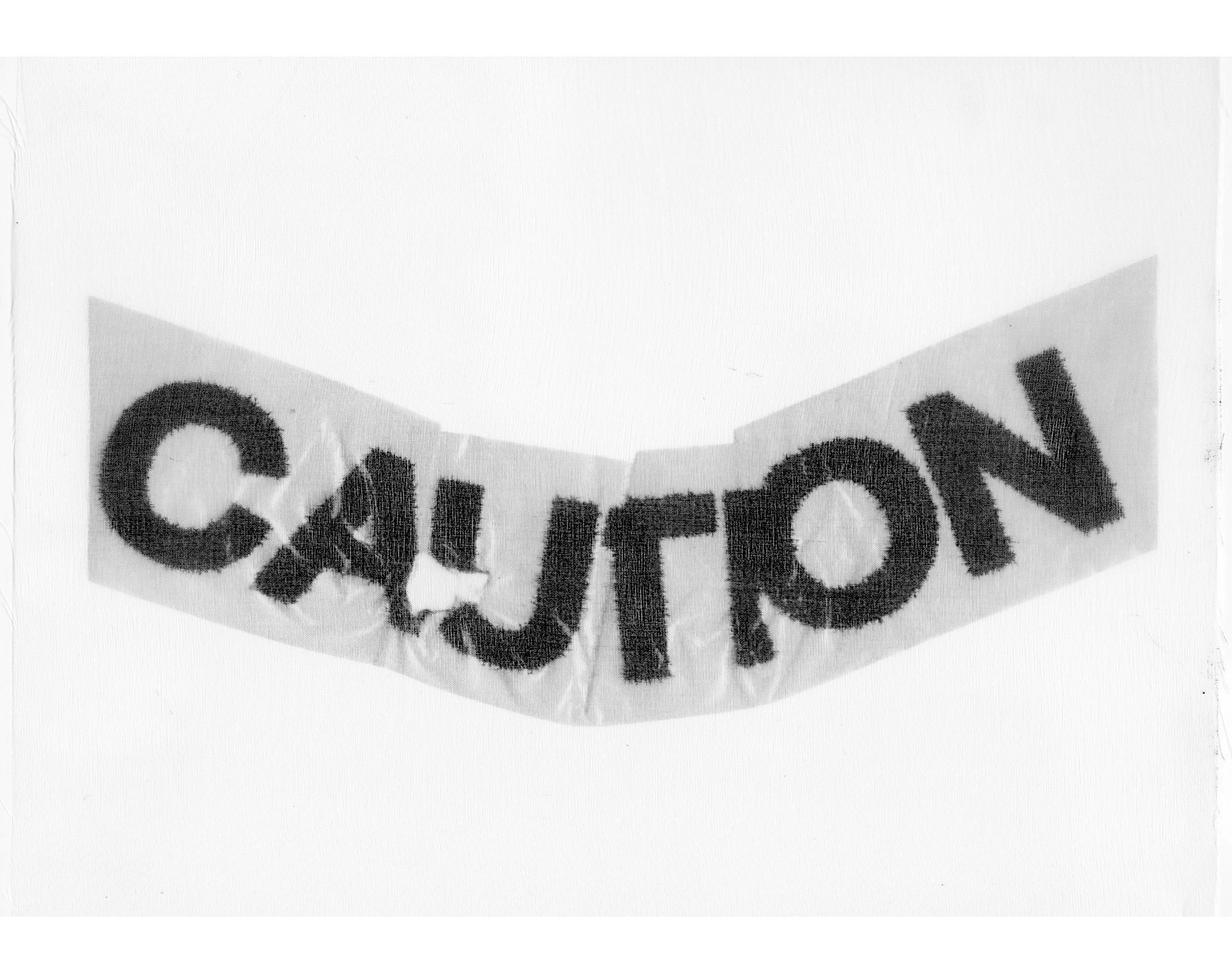 Closeup B and W original printed fabric used to create ‘caution’ mask. Text bleeds into the transparent fiber.